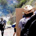 Varios manifestantes se disponen a lanzar botellas contra las fuerzas de seguridad en una calle de Caracas