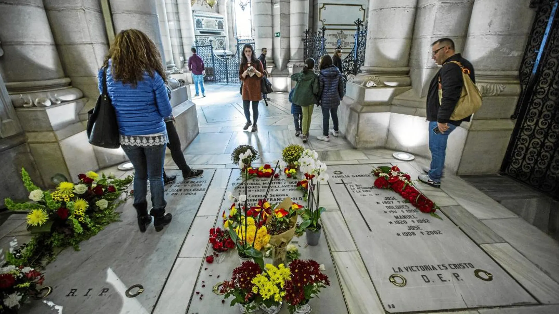 Visitantes de la catedral observan las flores depositadas en el enterramiento de la familia Franco en la catedral de la Almudena