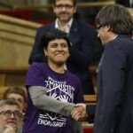 El presidente de la Generalitat, Carles Puigdemont (dcha.), saluda a la diputada de la CUP Anna Gabriel (izq.)