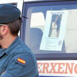Un agente de la Guardia Civil de los que participan en el dispositivo de búsqueda, con la foto de Diana Quer detrás
