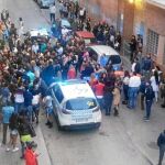 La gente rodea a un coche patrulla durante la redada en un bar de la calle san Enrique de Tetuán