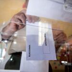 Una persona deposita en una urna de un colegio electoral