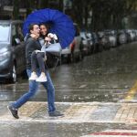 Una pareja cruza una calle de Salou inundada a causa del frente que esta azotando Cataluña
