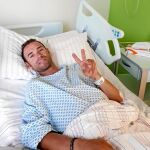 Valverde hace el signo de la victoria tras ser operado de una fractura en la rótula en Düsseldorf. El ciclista murciano se recupera bien.