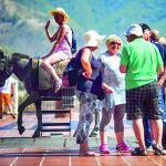 Una turista subida al monumento del burro-taxi en la localidad malagueña de Mijas.