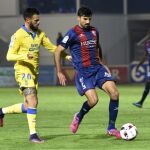 El centrocampista del Huesca Juan Aguilera (d) disputa un balón con el delantero Tyronne del Pino (i), de Las Palmas