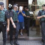 Efectivos de la Guardia Civil y Mossos d'Esquadra custodian a uno de los detenidos.