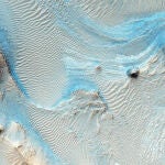 Imagen de Nili Fossae, donde puede apreciarse un lecho de roca en capas horizontales como estrías en los sedimentos de tonos claros en el suelo de un cañón cerca de Syrtis Major