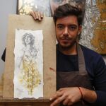 El autor Manuel Peña junto al cartel de la Asociación de Belenistas