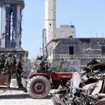 Fuerzas leales al presidente Asad pasan frente a la torre del reloj de la plaza en Qusair, ayer