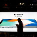 Imagen de archivo muestra a hombre mientras pasea frente a un anuncio del modelo iPhone X en Pekín (China) / EFE