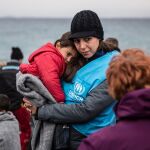 Una trabajadora de ACNUR da calor a un niño refugiado tras llegar en bote a la isla griega de Lesbos