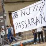 Habitantes de Arenys de Munt pasan detrás de un cartel con un «No pasarán» y un piolín dibujado