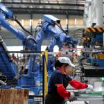 Una trabajadora de una fábrica de componentes robotizada