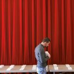 Un joven elige su papeleta en un colegio electoral en Gerona antes de la jornada de votación