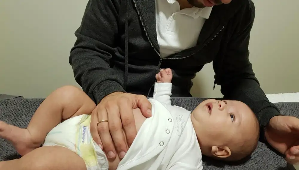 El fisio haciendo movimientos en el abdomen del bebé, de 2 meses, que sufre cólicos del lactante