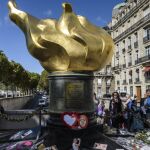Varias personas dejan flores y fotografías en el monumento de la Llama de la Libertad sobre el puente del Almá.
