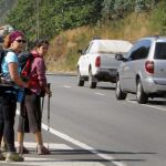 Unas peregrinas observan el tráfico en el camino de Santiago