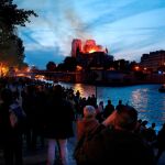 Decenas de personas en la orilla del Sena observan la columna de humo y las llamas que consumen a la catedral de Notre Dame. Efe