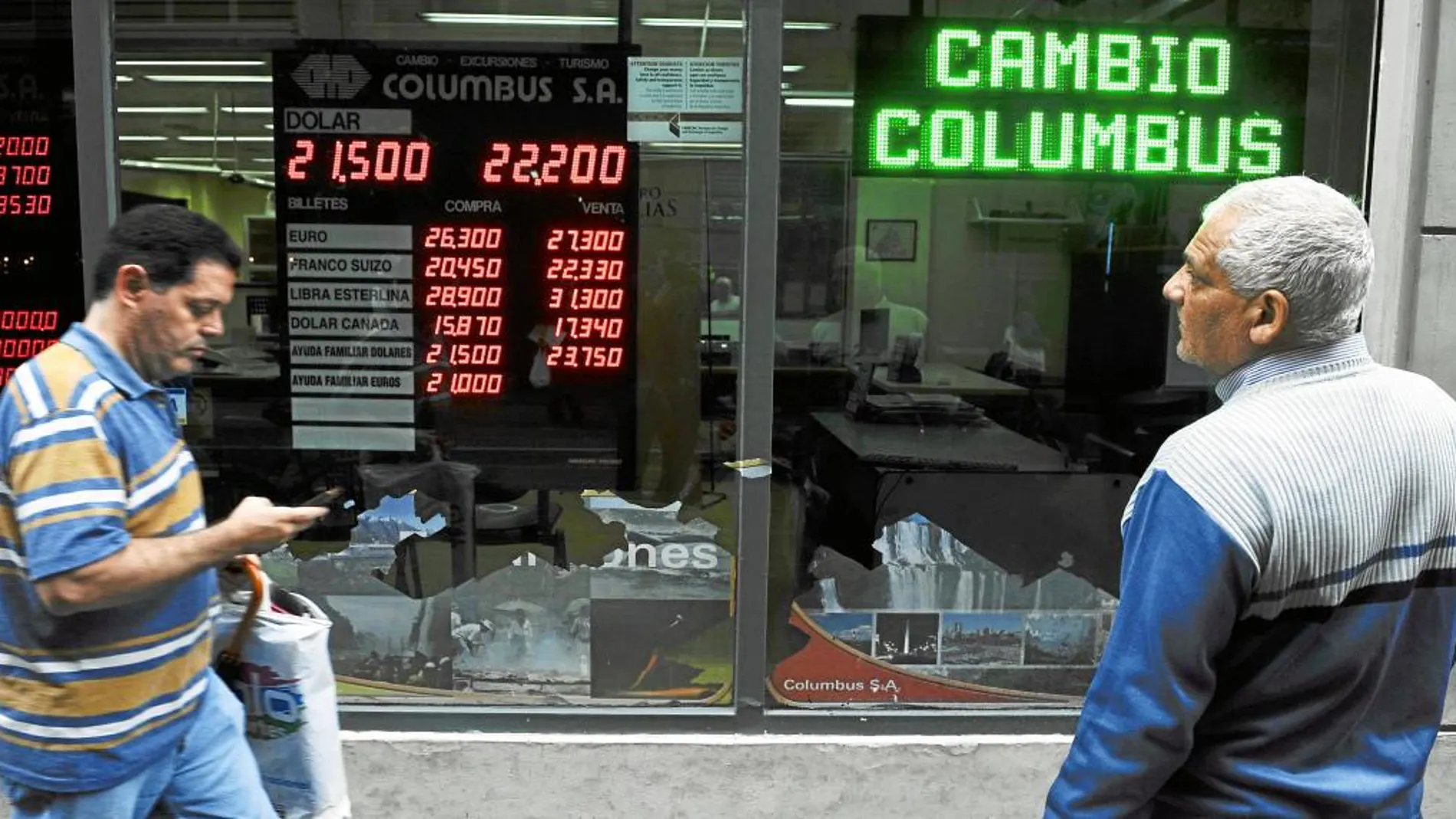 Dos argentinos pasan junto a una oficina de cambio de moneda, ayer, en Buenos Aires
