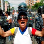 Un miembro de la oposición celebra el éxito de la protesta de ayer entre varios policías / Reuters