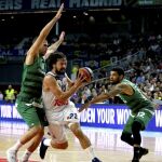 El base del Real Madrid Sergio Llull (c) entra a canasta entre el base del Panathinaikos Superfoods Athens, Eleftherios Bochoridis (i), y el escolta estadounidense James Feldeine (d)