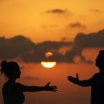 Una pareja haciendo meditación en un atardecer