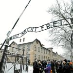 Un grupo de turistas delante de la icónica entrada al campo de concentración de Auschwitz