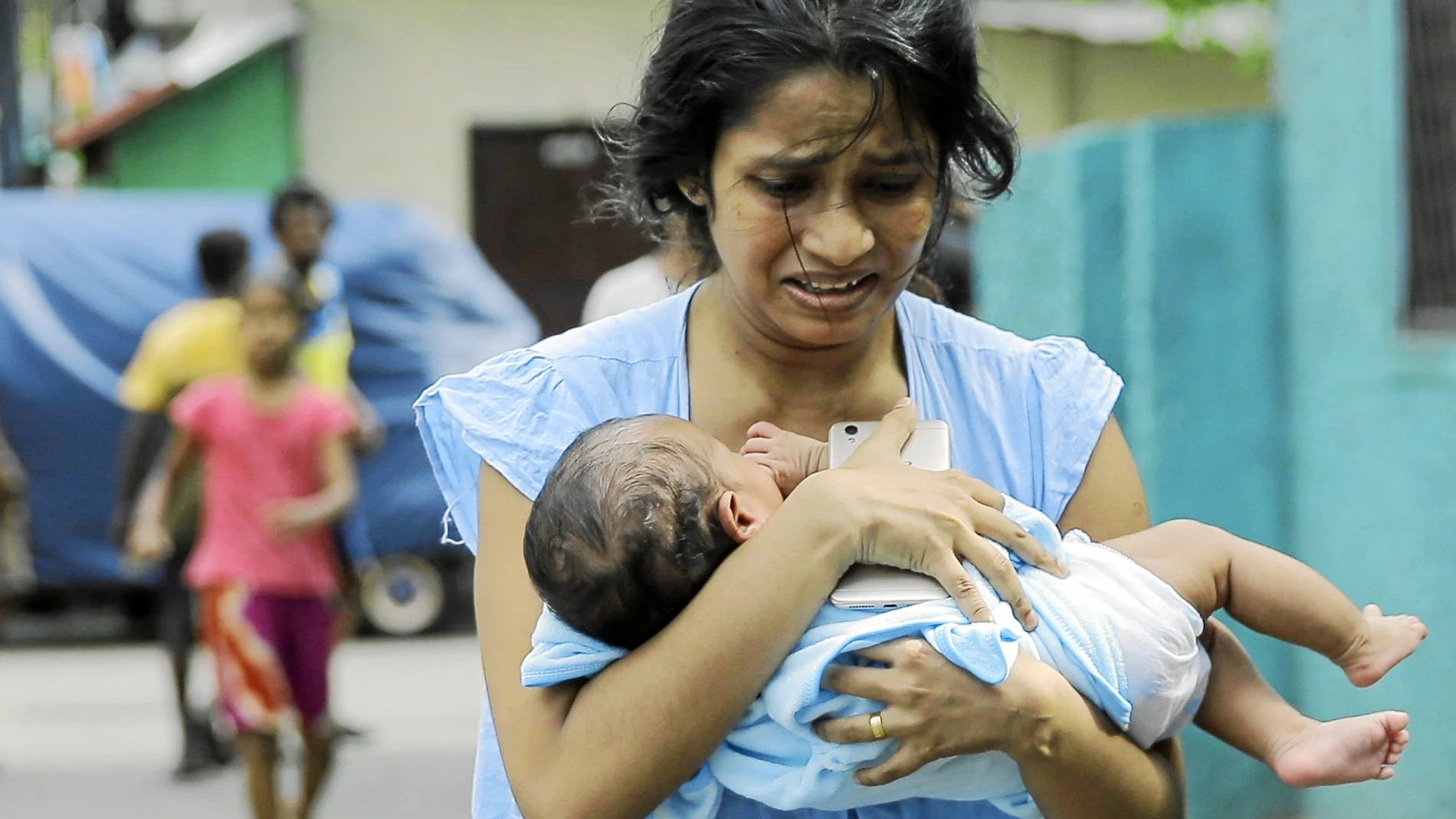 Una mujer corre con su bebé tras la explosión ayer de un vehículo aparcado en una calle de Colombo, la capital de Sri Lanka / Ap
