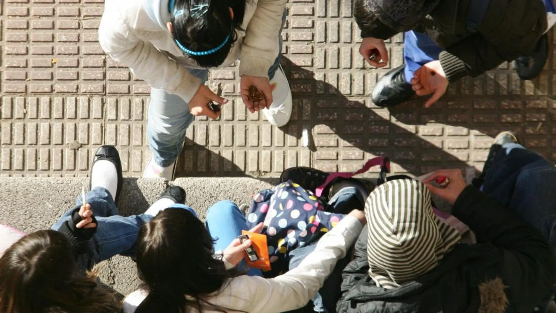 Un grupo de adolescentes se reúne en la calle para fumar un porro de cannabis