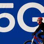 Un ciclista pasa ante un cartel de redes 5G instalado en las inmediaciones de la Fira de Barcelona / Efe