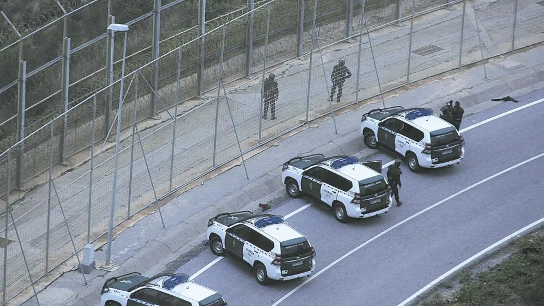 Varios vehículos de la Guardia Civil protegían ayer la frontera de Ceuta, que Interior reforzará con 19 agentes más tras la avalancha de esta semana