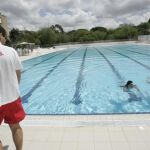 Imagen de archivo de un socorrista mira con atención a dos bañistas en una piscina