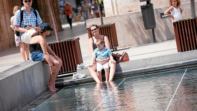 Varios turistas se refrescan en la plaza de la Almoina durante el pasado verano