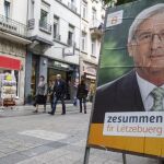 Un hombre pasa junto a un cartel electoral del actual primer ministro de Luxemburgo y candidato del CSV, Jean-Claude Juncker