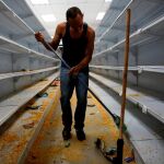 Un trabajador limpia un comercio saqueado en disturbios/Reuters