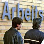 Tres hombres delante de la entrada de una oficina estatal de desempleo en Saarbruecken, Alemania.