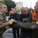 Policías y soldados israelíes retiran los restos de un cohete lanzado desde Gaza.