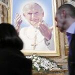Varios fieles pasan frente a una imagen del Pontífice Juan Pablo II, situada en el altar de una iglesia en el centro de la ciudad de Roma.