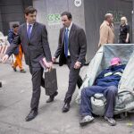 EMPOBRECIMIENTO. Dos oficinistas pasan al lado de un «sin techo» que recicla cartones para vivir en el distrito financiero de Buenos Aires