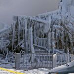 Un bombero, junto a la residencia quemada y cubierta de carámbanos de hielo tras el incendio