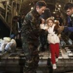Los servicios de rescate ayudan a una niña a bajar de un avión.