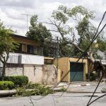 Vista general de una calle bloqueada por árboles y postes de luz caídos por fuertes vientos