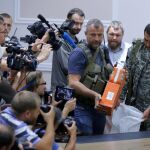 Un soldado separatista sostiene una de las dos cajas negras del vuelo MH17 de Malaysian Airlines antes de ser entregada al coronel Mohamed Sakri