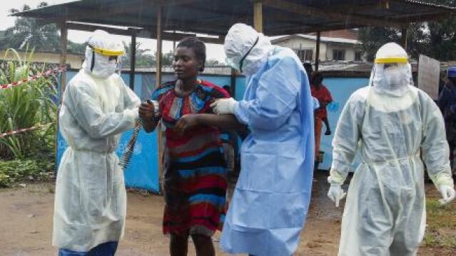 Unos enfermeros liberianos escoltan a una mujer supuestamente infectada con el virus del ébola al interior del hospital John F. Kennedy