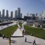 Obreros caminando con los rascacielos de Dubai al fondo