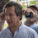 Un técnico ayuda al vicesecretario general de Organización del PP y director de su campaña electoral, Carlos Floriano, a colocarse un micrófono al comienzo del acto de Nuevas Generaciones del PP en Sevilla