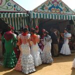 Mujeres vestidas de flamenca a las puertas de varias casetas