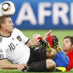 Podolski y Xabi Alonso pugnan por un balón durante el partido de semifinales del Mundial de Suráfrica 2010