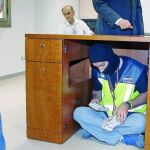 Un policía cuenta el dinero debajo del escritorio, como hicieron los timadores
